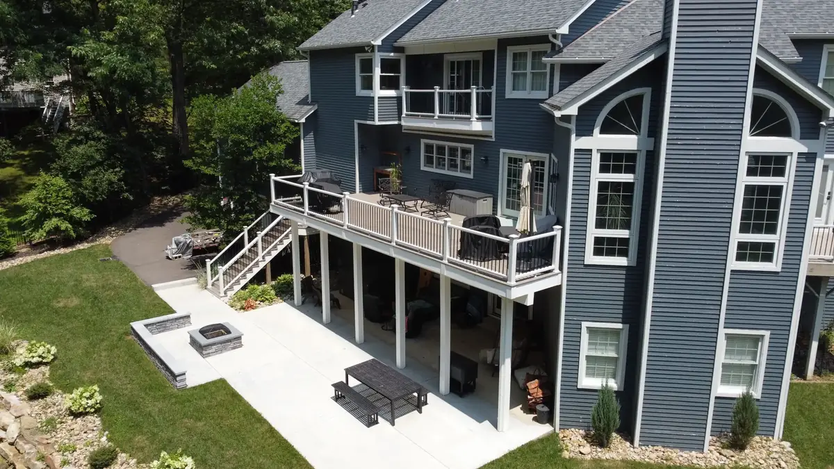 Two-story deck with white railing and stairs down to a patio with a fire pit