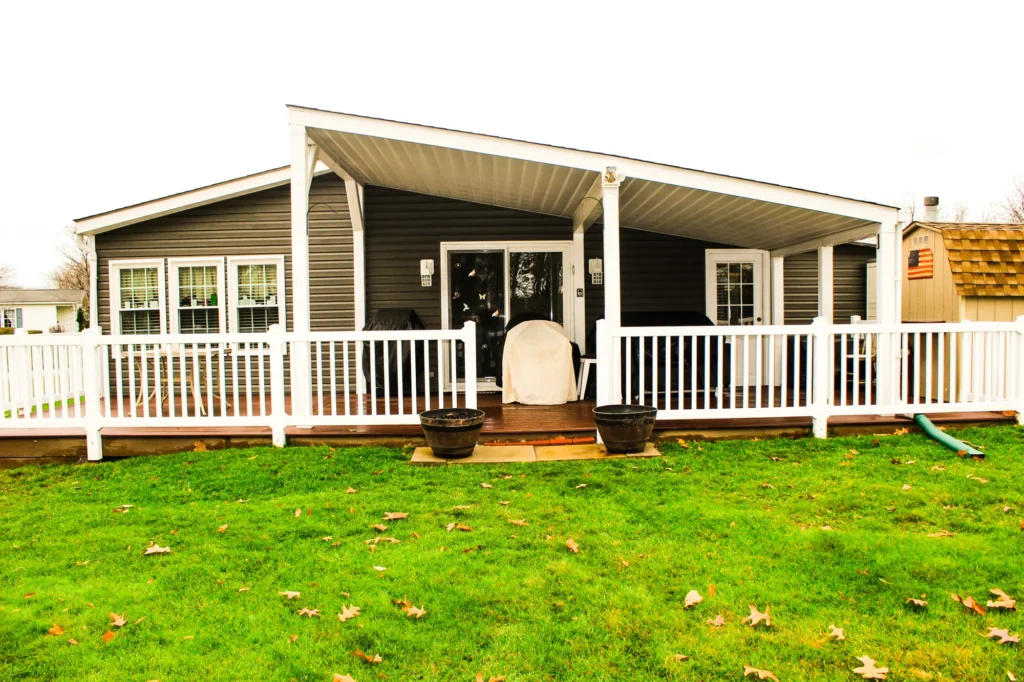 Photo of the entrance to a house, showing a deck with a roof and a white railing