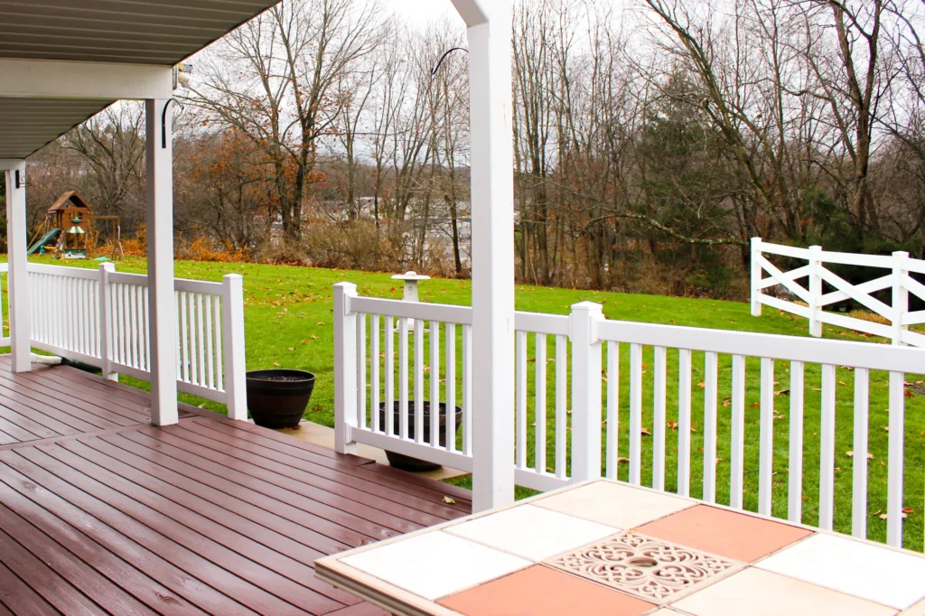 Photo of a house deck with a white railing and a roof