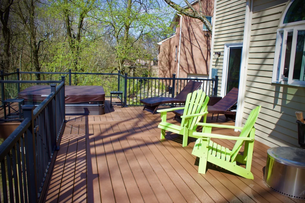 Photo of a deck featuring chairs and a hot tub, and the entire deck is surrounded by a black fence