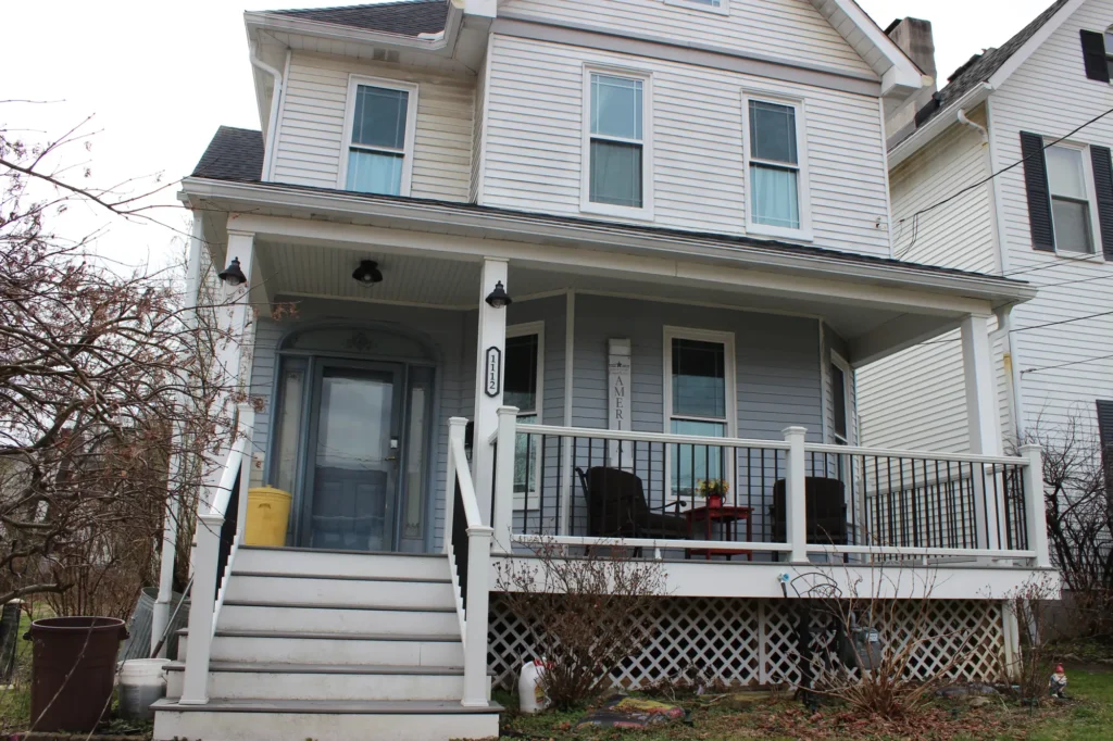 Photo of a white and cyan house with a deck and roof
