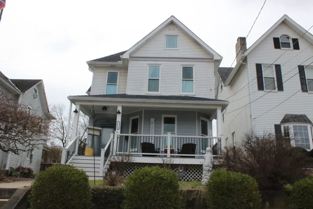 Photo of a white and cyan house with a deck and roof